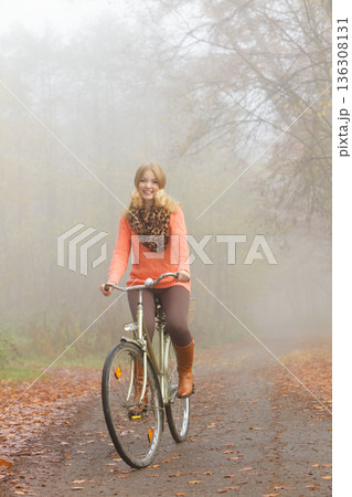 Active woman riding bike in autumn park. 136308131
