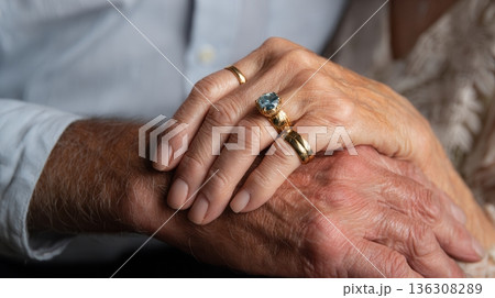 Elderly hands clasped wearing gold rings 136308289