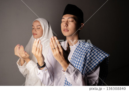 Man and woman united in prayer with calm expressions and soft illumination 136308840