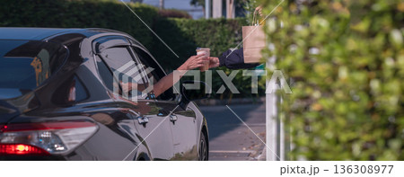 Hand Man in car receiving coffee in drive thru fast food restaurant. 136308977