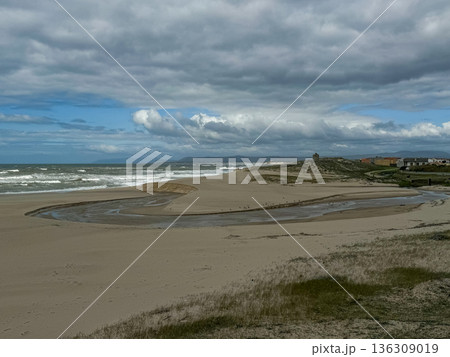 Wide coastal landscape in Povoa de Varzim, Portugal with sandy dunes, river mouth and Atlantic Ocean under dramatic cloudy sky 136309019