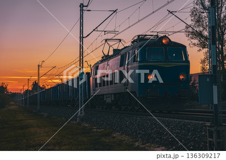 Freight train moving at sunset in warm golden tones Freight train moving at sunset in warm golden tones 136309217