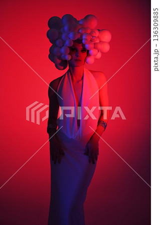 Avant-garde fashion woman wearing sculptural headpiece and white gown 136309885