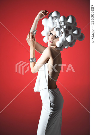 Fashion model posing in avant-garde white dress with spheres 136309887