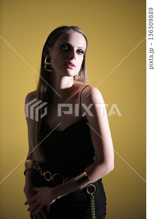 Woman posing wearing statement golden jewelry and black dress Woman posing wearing statement golden jewelry and black dress 136309889