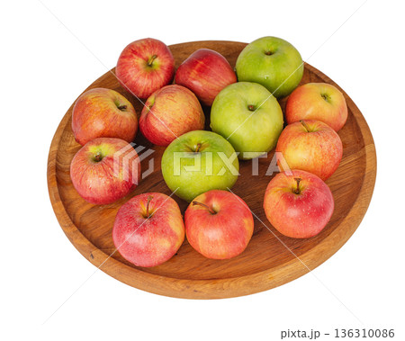 Red and green apples on a wooden plate isolated on white. Red and green apples on a wooden plate isolated on white. 136310086
