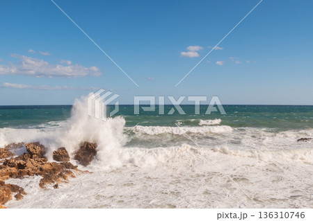 Cretan seascape in windy weather with strong surf and white foam on the sea. Cretan seascape in windy weather with strong surf and white foam on the sea. 136310746