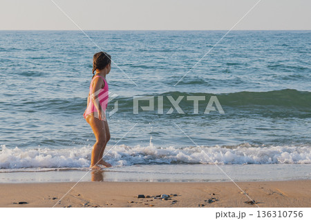 Little girl walking out of sea with blank copy space, child having fun on ocean beach during summer vacation, family travel and water resort concept Little girl walking out of sea with blank copy space, child having fun on ocean beach during summer vacation, family travel and water resort concept 136310756