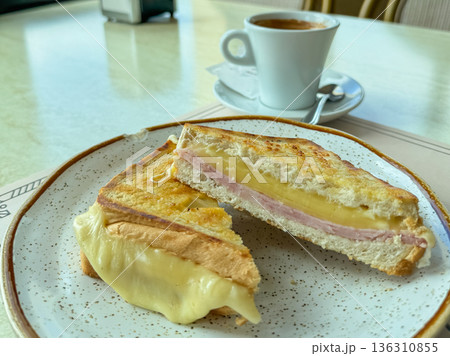 Grilled ham cheese sandwich breakfast plate, toasted bread with melted cheese and ham on ceramic plate, warm tones and cafe interior background, selective focus Grilled ham cheese sandwich breakfast plate, toasted bread with melted cheese and ham on ceramic plate, warm tones and cafe interior background, selective focus 136310855