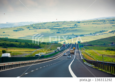 cars on Romania highway. asphalt road to mountain. vast summer landscape in dappled light. transportation background of europe. picturesque motorway wallpaper on a sunny day 136311292