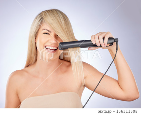 Portrait, happy hair care and woman with straightener for a professional salon treatment. Smile, health and an excited young model or girl with an iron from hairdresser for a hairstyle on a backdrop Portrait, happy hair care and woman with straightener for a professional salon treatment. Smile, health and an excited young model or girl with an iron from hairdresser for a hairstyle on a backdrop 136311308