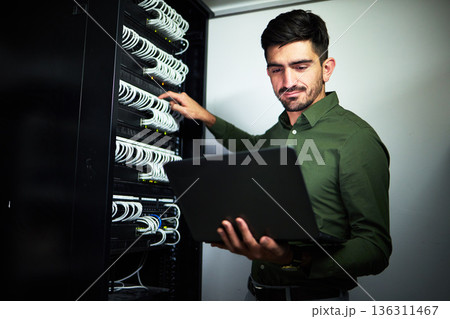 Laptop, engineering and man technician in a server room for technical repairs by a control box. Technology, maintenance and professional male electrician working on computer for cybersecurity system. 136311467