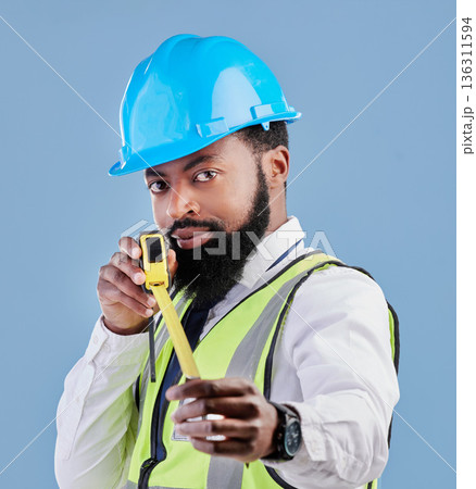 Black man, portrait and architect with measuring tape for construction against a blue studio background. Face of African male person, engineer or contractor in architecture planning with measure tool Black man, portrait and architect with measuring tape for construction against a blue studio background. Face of African male person, engineer or contractor in architecture planning with measure tool 136311594