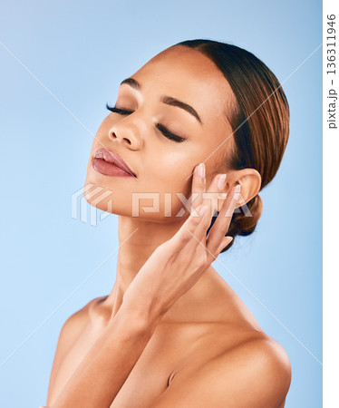 Woman, touch face and beauty, makeup and skincare with shine and manicure isolated on blue background. Female model, hand with dermatology and facial, healthy skin glow and cosmetic care in a studio 136311946