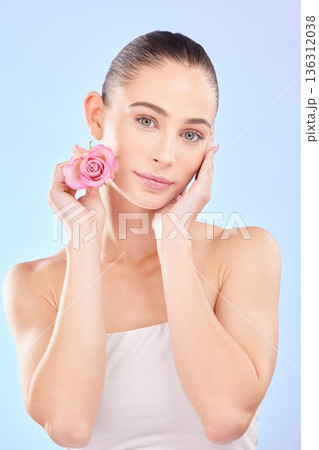 Woman, portrait and rose for skincare in studio, eco cosmetics and natural aesthetic facial on blue background. Face, female model and beauty of pink flowers, sustainable shine and floral dermatology Woman, portrait and rose for skincare in studio, eco cosmetics and natural aesthetic facial on blue background. Face, female model and beauty of pink flowers, sustainable shine and floral dermatology 136312038
