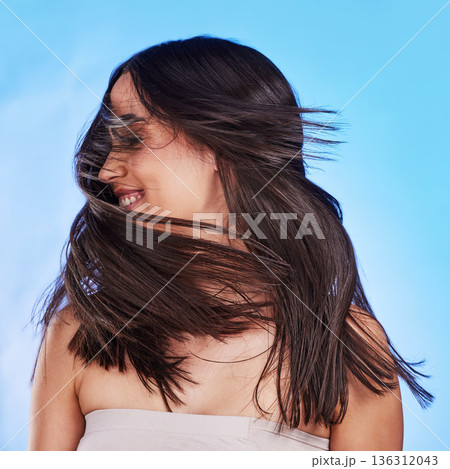 Woman, shake hair and beauty with shine, volume and texture against a blue studio background. Growth, person and model satisfied with salon treatment, glow and change with self care, playful and fun 136312043