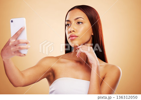 Studio, beauty or selfie with woman on social media to post picture or photo online on internet blog. Pictures, girl influencer or female model isolated on brown background for skincare or self care Studio, beauty or selfie with woman on social media to post picture or photo online on internet blog. Pictures, girl influencer or female model isolated on brown background for skincare or self care 136312050