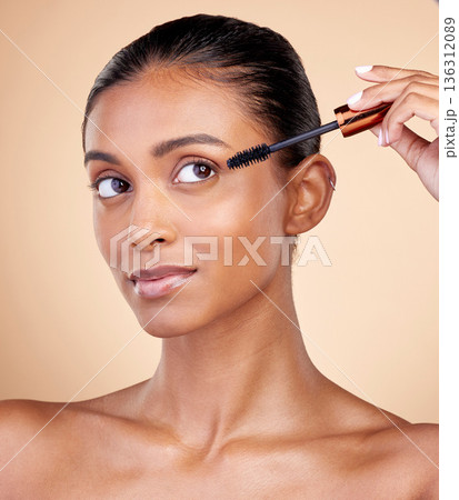 Beauty, makeup and mascara with face of woman in studio for cosmetics, eyelashes and glamour. Self care, application and tools with female model on brown background for product, volume and glow Beauty, makeup and mascara with face of woman in studio for cosmetics, eyelashes and glamour. Self care, application and tools with female model on brown background for product, volume and glow 136312089