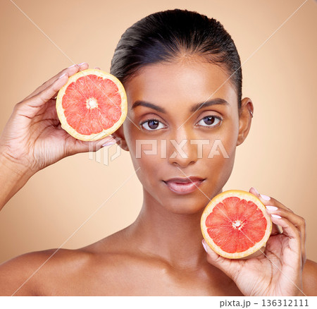 Grapefruit, portrait and beauty of woman in studio for vitamin c benefits, eco cosmetics and nutrition. Face of indian female model, natural skincare and healthy citrus food for aesthetic dermatology 136312111