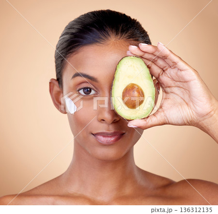 Woman, avocado and cream for face skincare, natural beauty or vitamin c benefits on studio, brown background. Young person or model in portrait for with green fruits, eye moisturizer and dermatology Woman, avocado and cream for face skincare, natural beauty or vitamin c benefits on studio, brown background. Young person or model in portrait for with green fruits, eye moisturizer and dermatology 136312135