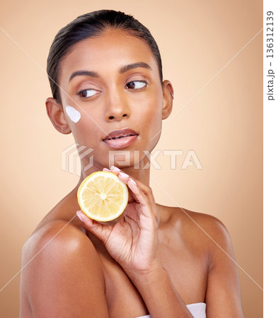 Woman, thinking and cream with lemon for skincare, cosmetics and natural beauty product or vitamin c benefits. Facial sunscreen of young person with fruits for dermatology on studio, brown background 136312139