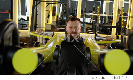 Man training on chest press machine in gym Man training on chest press machine in gym 136312172