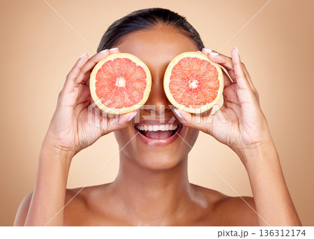 Grapefruit, beauty and eyes of happy woman in studio, vitamin c nutrition or natural glow. Face of female model, healthy skincare or smile with citrus fruits, eco dermatology or sustainable cosmetics Grapefruit, beauty and eyes of happy woman in studio, vitamin c nutrition or natural glow. Face of female model, healthy skincare or smile with citrus fruits, eco dermatology or sustainable cosmetics 136312174