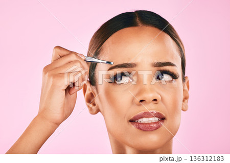 Pain, face and woman with tweezer for hair removal in studio isolated on a pink background. Beauty, facial and eyebrow plucking of model for self care, skincare and wellness, aesthetic and cosmetic Pain, face and woman with tweezer for hair removal in studio isolated on a pink background. Beauty, facial and eyebrow plucking of model for self care, skincare and wellness, aesthetic and cosmetic 136312183