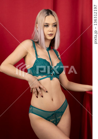 Woman posing with green lingerie on red background 136312197