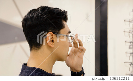 Man adjusting eyewear frame near shop display Man adjusting eyewear frame near shop display 136312211