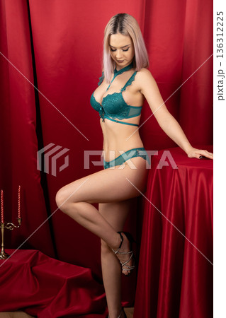 Woman in green lingerie leaning on red table 136312225