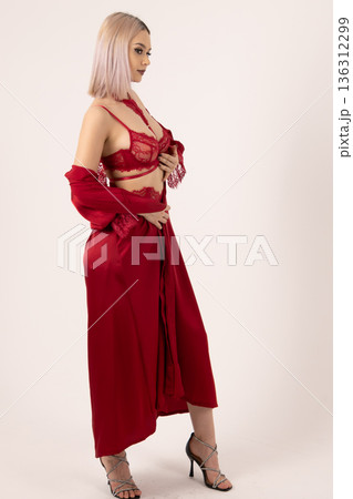 Woman in red silk robe looking away in studio 136312299