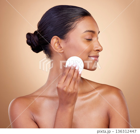 Woman, cotton pad and skincare of face cosmetics for aesthetic wellness on studio background. Happy indian female model, clean beauty and facial dermatology product for makeup removal, shine and glow Woman, cotton pad and skincare of face cosmetics for aesthetic wellness on studio background. Happy indian female model, clean beauty and facial dermatology product for makeup removal, shine and glow 136312447