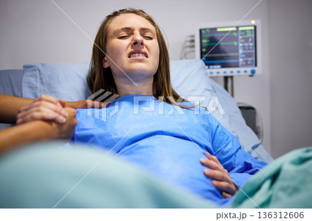 Pregnant woman, hospital and delivery with push, holding hands and support in bed, baby and pain. Strong mother, labor and helping hand in clinic bed for infant child, motivation and new life 136312606