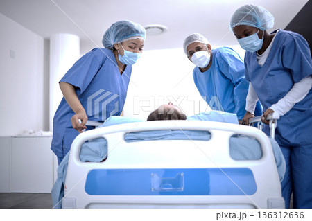 Covid, surgery and doctors with a patient for a check, healthcare support and consultation. Hospital, medical and surgeons or nurses helping a sick patient in a bed with face mask for nursing 136312636