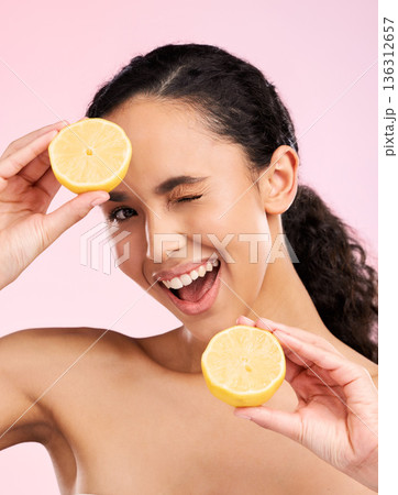 Woman, beauty and lemon for wink in studio portrait, smile and natural skin glow by pink background. Latino girl, model and fruit for cosmetics, eye emoji and detox for wellness, nutrition and shine Woman, beauty and lemon for wink in studio portrait, smile and natural skin glow by pink background. Latino girl, model and fruit for cosmetics, eye emoji and detox for wellness, nutrition and shine 136312657