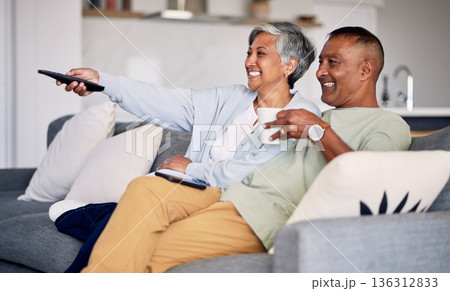 Senior couple, watching tv and relax on couch in home living room, laugh and together for funny comedy show. Elderly man, old woman and remote control for video, comic movie and lounge sofa in house Senior couple, watching tv and relax on couch in home living room, laugh and together for funny comedy show. Elderly man, old woman and remote control for video, comic movie and lounge sofa in house 136312833