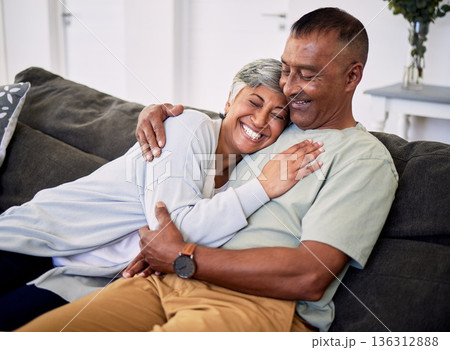 Hug, marriage and senior woman or man on sofa with love or care in home to relax. Retirement, smile and elder couple with embrace in living room for bonding together or quality time in house. 136312888