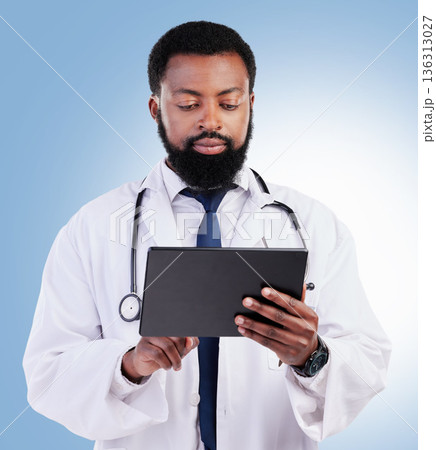 Healthcare, tablet and a black man doctor in studio on a blue background for cardiology research. Medical, technology and innovation with a male medicine professional searching for information online Healthcare, tablet and a black man doctor in studio on a blue background for cardiology research. Medical, technology and innovation with a male medicine professional searching for information online 136313027