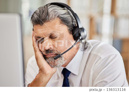 Tired, call center and male consultant sleeping in his office while doing an online consultation. Exhausted, burnout and mature man telemarketing or customer support agent with a headset in workplace 136313116