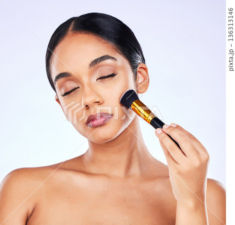 Makeup brush, beauty and cosmetics of a happy woman in studio for skincare, self care and cosmetology. Skin glow, shine and wellness of a female model with facial application tools for foundation 136313146