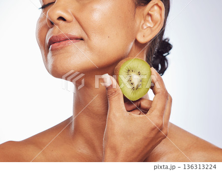 Beauty, skincare and mature woman with kiwi in studio isolated on a white background. Food, fruit and natural model with nutrition for wellness, healthy diet and vitamin c for anti aging cosmetics. Beauty, skincare and mature woman with kiwi in studio isolated on a white background. Food, fruit and natural model with nutrition for wellness, healthy diet and vitamin c for anti aging cosmetics. 136313224