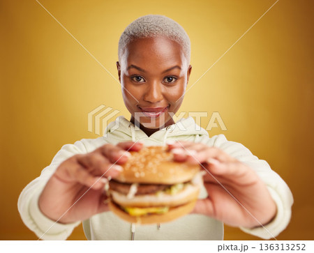 Burger, offer and portrait of woman or student on studio yellow background in restaurant promotion or deal. Giving, eating and young african person for customer experience with fast food or hamburger Burger, offer and portrait of woman or student on studio yellow background in restaurant promotion or deal. Giving, eating and young african person for customer experience with fast food or hamburger 136313252