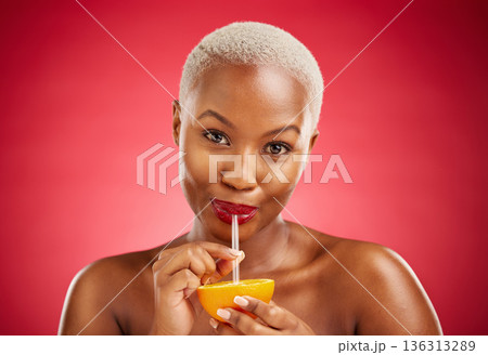 Black woman, portrait and drinking orange for vitamin C, diet or natural nutrition against a red studio background. African female person with organic citrus fruit, juice and straw on mockup space Black woman, portrait and drinking orange for vitamin C, diet or natural nutrition against a red studio background. African female person with organic citrus fruit, juice and straw on mockup space 136313289