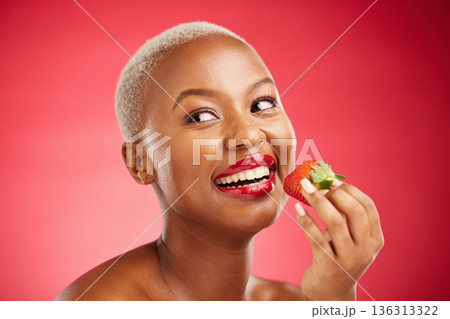 Beauty, thinking face and a woman with a strawberry on a red background for health and wellness. Black female aesthetic model with a smile, makeup and fruit for nutrition and healthy diet in studio 136313322