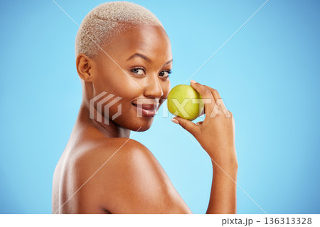 Happy black woman, portrait and apple for nutrition or healthy diet against a blue studio background. African female person smile with natural organic green fruit for food snack, health and wellness 136313328