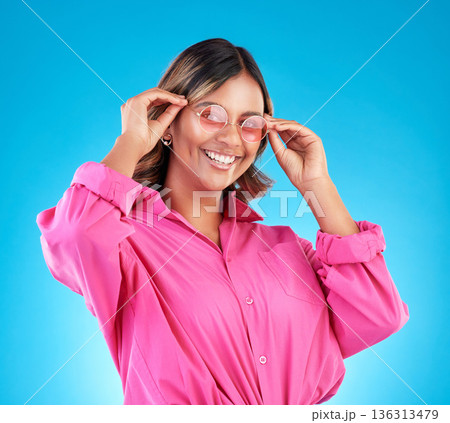 Fashion sunglasses, portrait and happy woman in studio isolated on a blue background. Face, glasses and Indian model with style, designer shades and positive mindset for aesthetic, gen z and smile 136313479