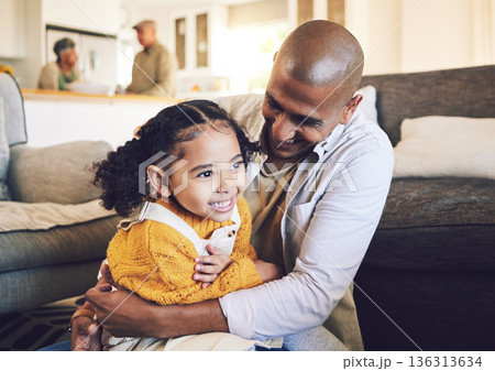 Happy family, smile and father with girl child on living room floor playing, laugh and bond in their home together. Love, hug and kid with parent in a lounge for tickle, fun and games on the weekend 136313634