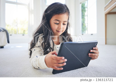 Young girl, tablet and game app or cartoon streaming online with internet, elearning and relax on carpet in house. Watch animation film, female kid at home and website, entertainment and subscription Young girl, tablet and game app or cartoon streaming online with internet, elearning and relax on carpet in house. Watch animation film, female kid at home and website, entertainment and subscription 136313721