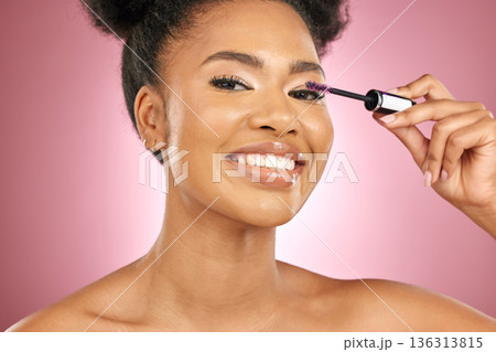 Makeup, mascara and beauty portrait of a woman for skincare, wellness and dermatology glow. Happy, eyelash and face cosmetics of a black female model with facial shine on a pink background in studio Makeup, mascara and beauty portrait of a woman for skincare, wellness and dermatology glow. Happy, eyelash and face cosmetics of a black female model with facial shine on a pink background in studio 136313815